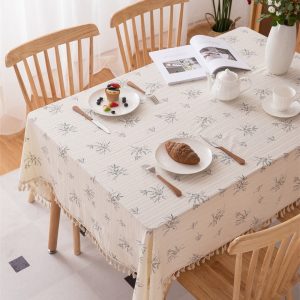 Natural cotton tablecloth with botanical print and tassel trim on a dining table
