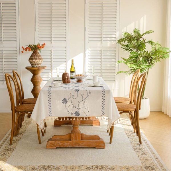 Beige polyester tablecloth with blue floral embroidery and tassel fringe, styled on a farmhouse dining table