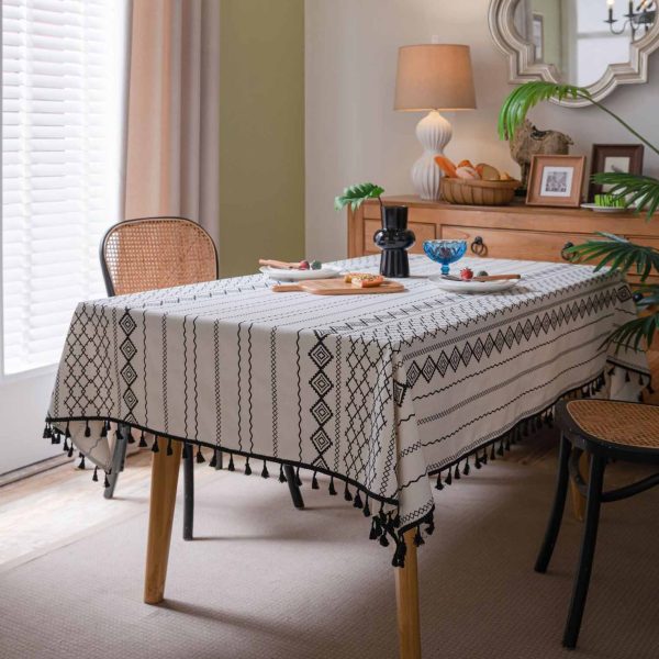 Black and white cotton-linen tablecloth with geometric tribal print and tassel fringe on a modern dining table