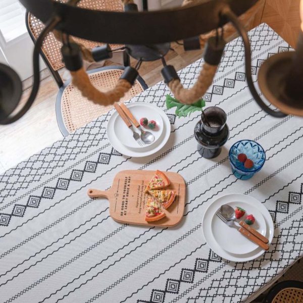 Black and white cotton-linen tablecloth with geometric tribal print and tassel fringe on a modern dining table