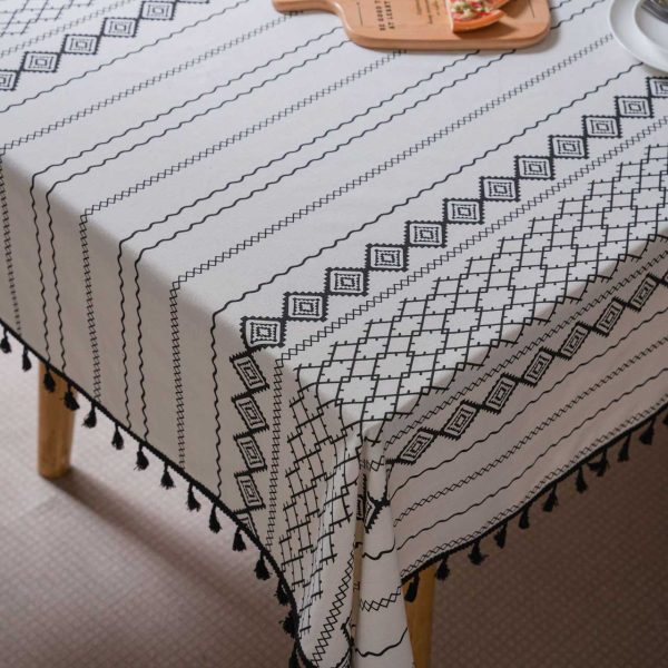 Black and white cotton-linen tablecloth with geometric tribal print and tassel fringe on a modern dining table