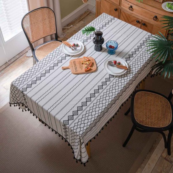 Black and white cotton-linen tablecloth with geometric tribal print and tassel fringe on a modern dining table