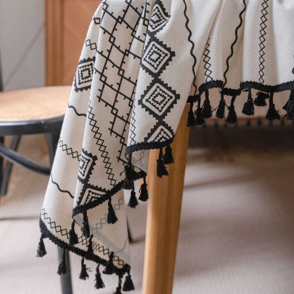 Black and white cotton-linen tablecloth with geometric tribal print and tassel fringe on a modern dining table