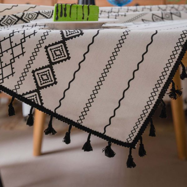 Black and white cotton-linen tablecloth with geometric tribal print and tassel fringe on a modern dining table
