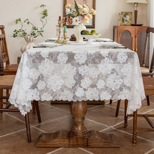 Dining table styled with white embroidered polyester tablecloth and floral centerpiece.