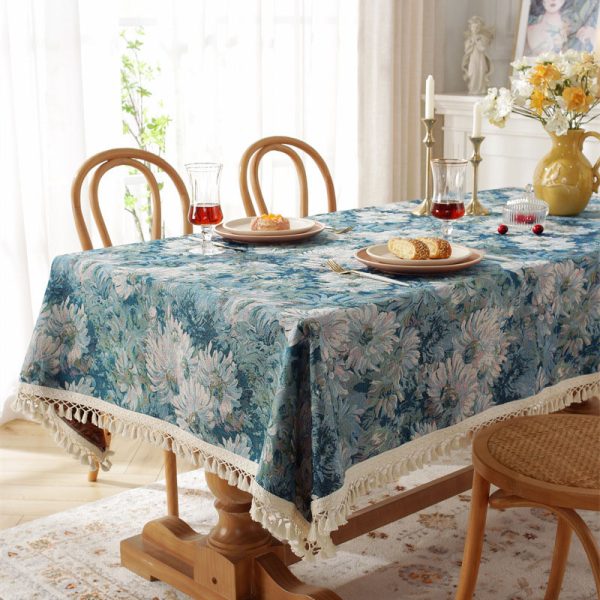 Woven cotton polyester tablecloth with blue daisy floral pattern and tassel trim on beige background – elegant and soft, perfect for dining table settings