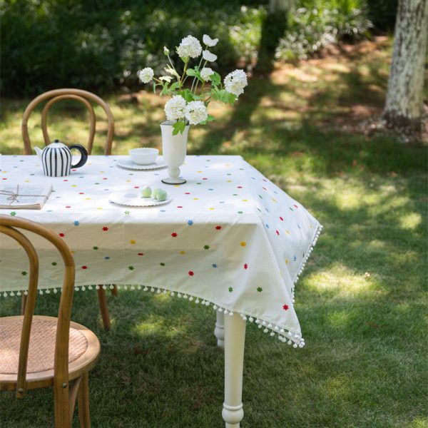 Cotton embroidered tablecloth with colorful floral embroidery and pom-pom edging, ideal for dining tables. Soft cotton blend material, perfect for home dining and special occasions.