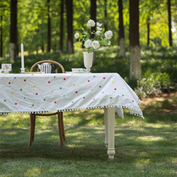 Cotton embroidered tablecloth with colorful floral embroidery and pom-pom edging, ideal for dining tables. Soft cotton blend material, perfect for home dining and special occasions.