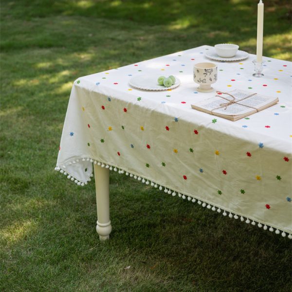 Cotton embroidered tablecloth with colorful floral embroidery and pom-pom edging, ideal for dining tables. Soft cotton blend material, perfect for home dining and special occasions.