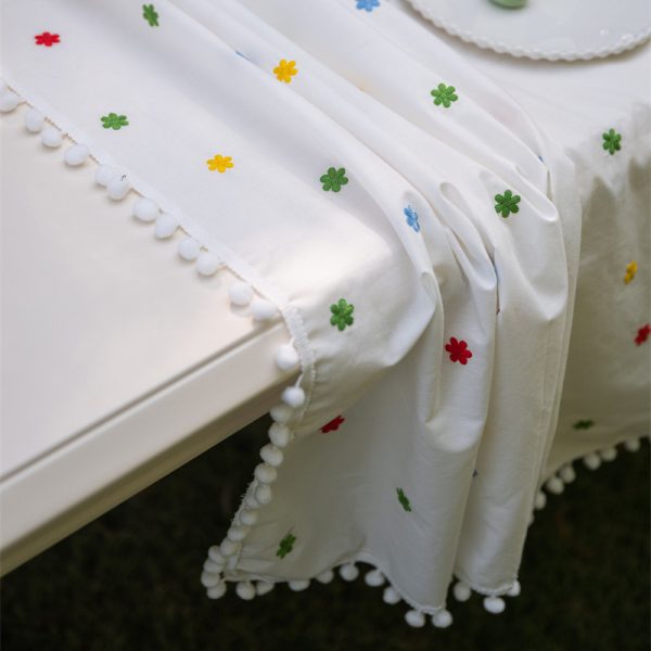 Cotton embroidered tablecloth with colorful floral embroidery and pom-pom edging, ideal for dining tables. Soft cotton blend material, perfect for home dining and special occasions.