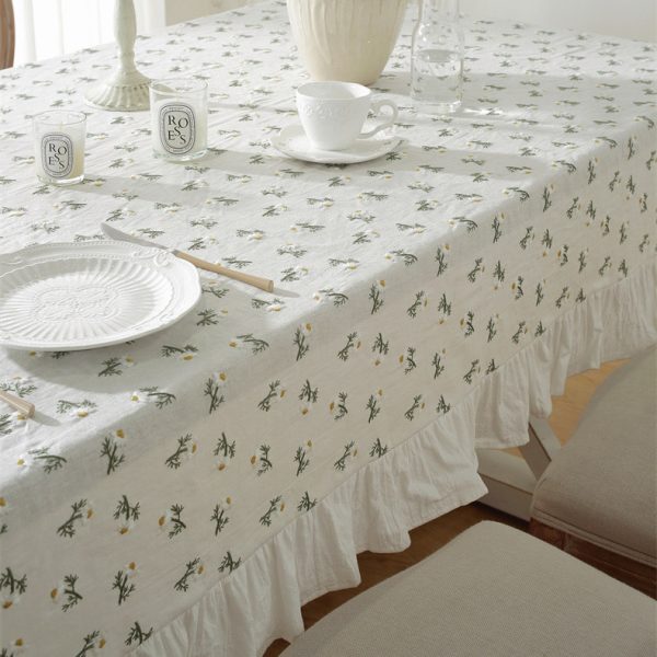 Linen tablecloth with 3D embroidered daisy flowers and ruffled edges, styled on a cozy dining table with wildflowers, creating a soft cottage-style atmosphere.