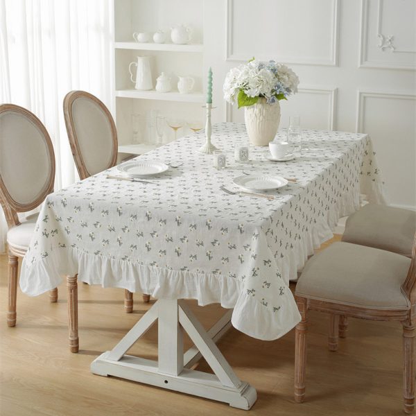 Linen tablecloth with 3D embroidered daisy flowers and ruffled edges, styled on a cozy dining table with wildflowers, creating a soft cottage-style atmosphere.