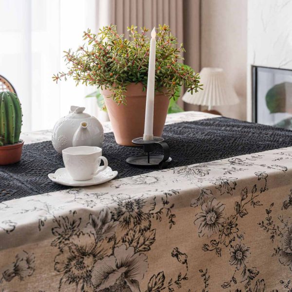 Beige floral cotton-linen tablecloth with black lace and tassels, styled in an elegant boho dining setup. Soft texture with vintage charm.