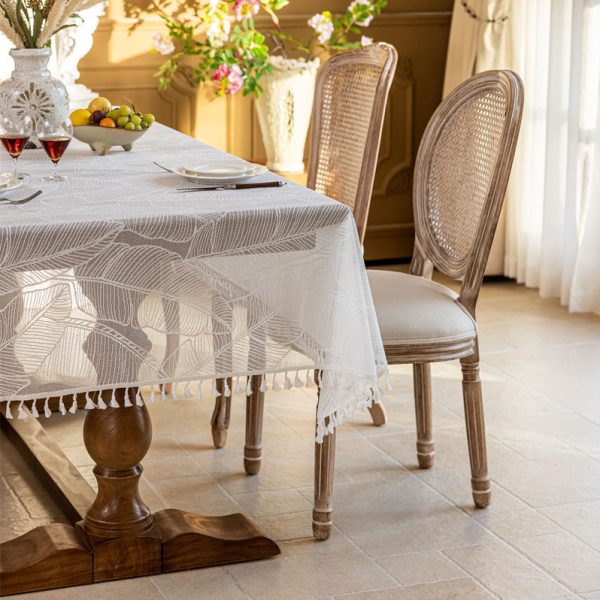 White polyester tablecloth with soft banana leaf print, lace trim, and tassel edge—styled for modern botanical or farmhouse dining.