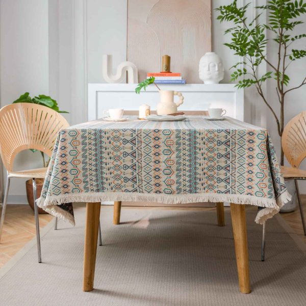 Boho-style cotton linen tablecloth with colorful geometric patterns and white tassel edges, styled in a rustic dining setting.