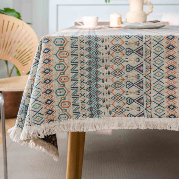 Boho-style cotton linen tablecloth with colorful geometric patterns and white tassel edges, styled in a rustic dining setting.