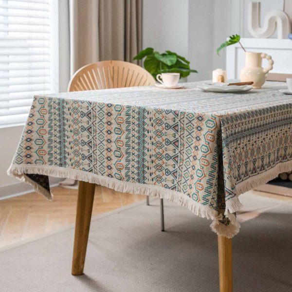 Boho-style cotton linen tablecloth with colorful geometric patterns and white tassel edges, styled in a rustic dining setting.