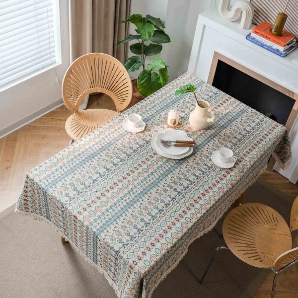 Boho-style cotton linen tablecloth with colorful geometric patterns and white tassel edges, styled in a rustic dining setting.
