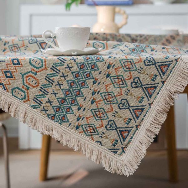 Boho-style cotton linen tablecloth with colorful geometric patterns and white tassel edges, styled in a rustic dining setting.