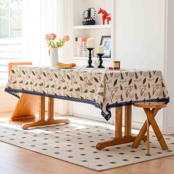 Cotton-linen tablecloth with willow leaf print and blue lace trim on a rustic wooden table