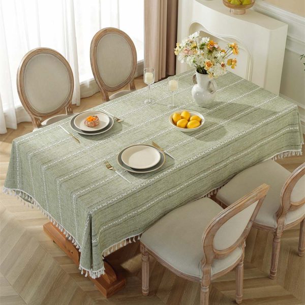 Green polyester tablecloth with white tassel trim and geometric pattern, styled on a dining table for modern home decor