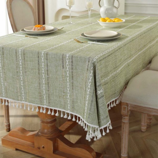 Green polyester tablecloth with white tassel trim and geometric pattern, styled on a dining table for modern home decor