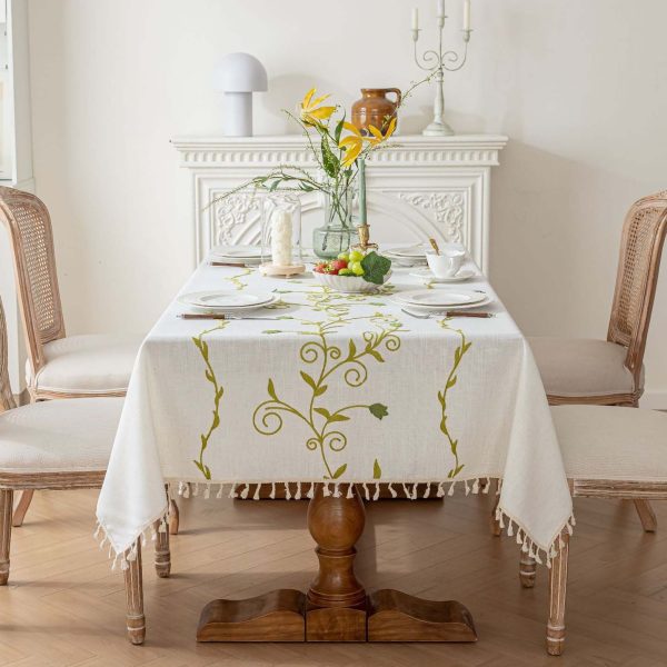 White polyester tablecloth with green floral embroidery on a dining table