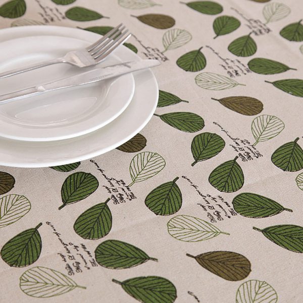 Poly-cotton tablecloth with green leaf print and delicate lace trim, featuring a soft and cozy farmhouse style. Ideal for everyday dining, outdoor meals, or family gatherings.