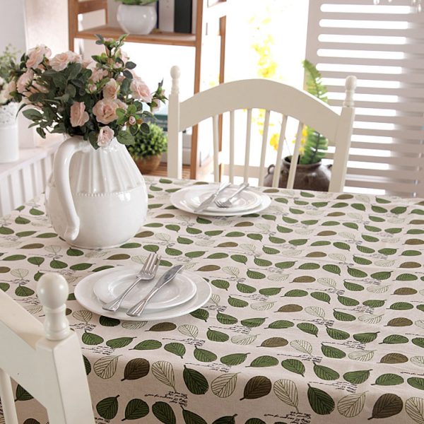 Poly-cotton tablecloth with green leaf print and delicate lace trim, featuring a soft and cozy farmhouse style. Ideal for everyday dining, outdoor meals, or family gatherings.