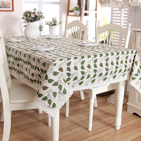 Poly-cotton tablecloth with green leaf print and delicate lace trim, featuring a soft and cozy farmhouse style. Ideal for everyday dining, outdoor meals, or family gatherings.