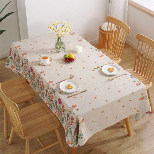 Colorful floral polyester-linen tablecloth with vintage botanical pattern on a light background, styled on a rustic dining table with glassware and wooden chairs.