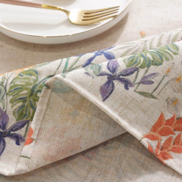 Colorful floral polyester-linen tablecloth with vintage botanical pattern on a light background, styled on a rustic dining table with glassware and wooden chairs.
