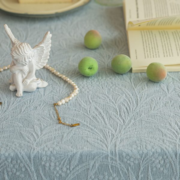 Elegant embossed leaf-pattern cotton blend tablecloth styled on a neutral-toned dining table with soft lighting and minimal decor.