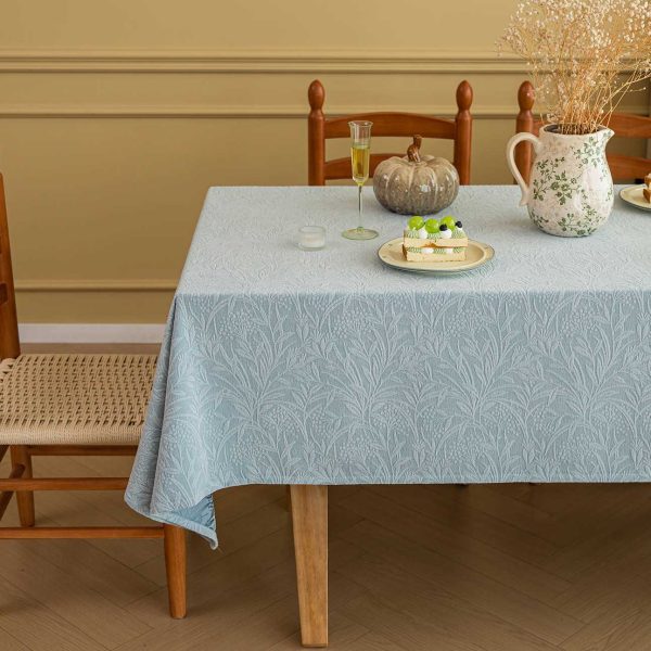 Elegant embossed leaf-pattern cotton blend tablecloth styled on a neutral-toned dining table with soft lighting and minimal decor.