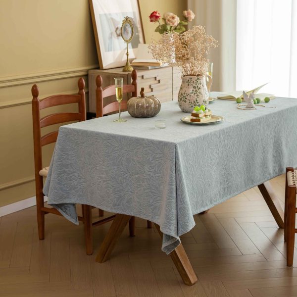 Elegant embossed leaf-pattern cotton blend tablecloth styled on a neutral-toned dining table with soft lighting and minimal decor.