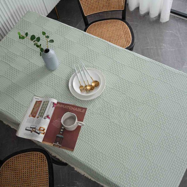 Light green geometric cotton blend tablecloth with tassel trim, styled on rustic and modern dining tables. Features include textured weave, soft fringe edges, and versatile use in kitchens and dining rooms.