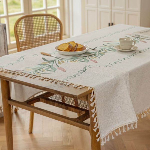 Beige faux linen tablecloth with brown embroidered leaf pattern and tassel fringe, made from polyester-linen blend, suitable for dining tables or outdoor settings.