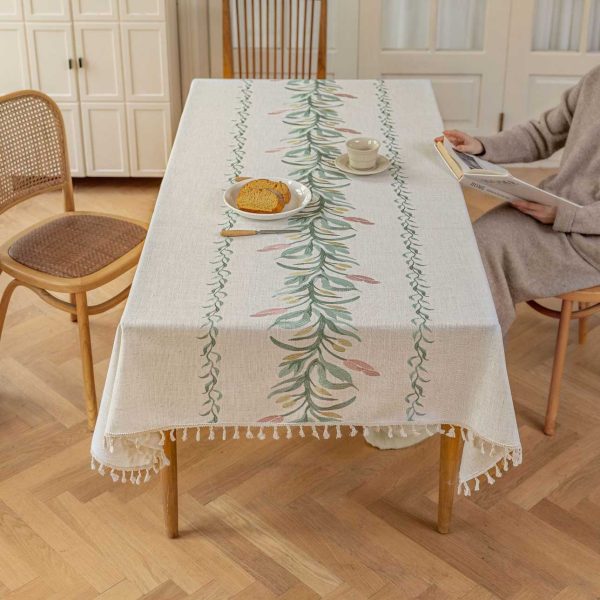 Beige faux linen tablecloth with brown embroidered leaf pattern and tassel fringe, made from polyester-linen blend, suitable for dining tables or outdoor settings.