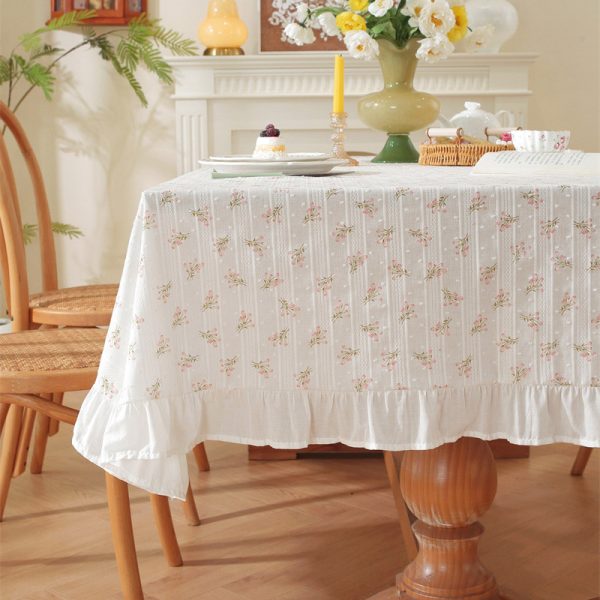 Cotton tablecloth with tulip floral print and ruffled edges, styled in a cottage-inspired dining room with soft lighting and rustic wooden accents.