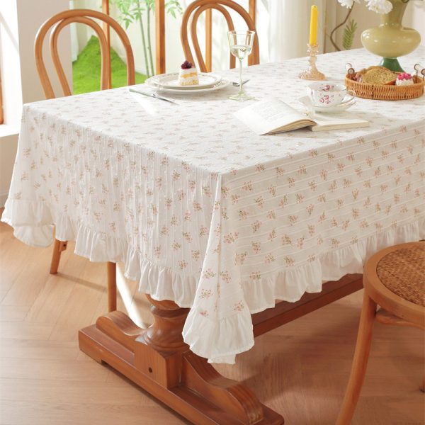 Cotton tablecloth with tulip floral print and ruffled edges, styled in a cottage-inspired dining room with soft lighting and rustic wooden accents.