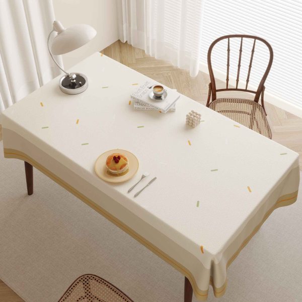Outdoor table setting with waterproof outdoor tablecloth in stripe and dot design, surrounded by greenery and sunlight.