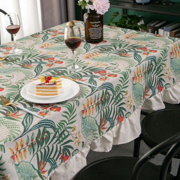 Tropical cotton-linen tablecloth with green palm and floral print, ruffled edge, styled in a light rustic dining setup.