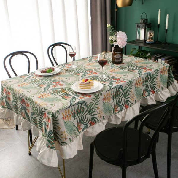Tropical cotton-linen tablecloth with green palm and floral print, ruffled edge, styled in a light rustic dining setup.