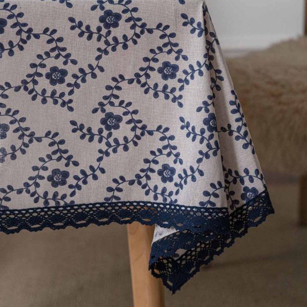 A hand-painted blue vine floral cotton linen tablecloth with navy lace trim, styled on a rustic wooden table with minimalist dinnerware and greenery.