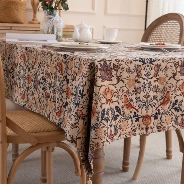 Vintage-style tablecloth featuring colorful floral and bird patterns, woven in a cotton-blend fabric with elegant tassel trim, perfect for farmhouse or cottage-style dining settings.