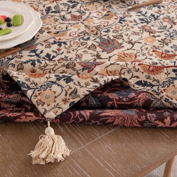 Vintage-style tablecloth featuring colorful floral and bird patterns, woven in a cotton-blend fabric with elegant tassel trim, perfect for farmhouse or cottage-style dining settings.