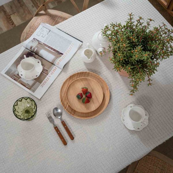 Beige waffle weave cotton-poly tablecloth with tassels, perfect for rustic or minimalist dining decor.