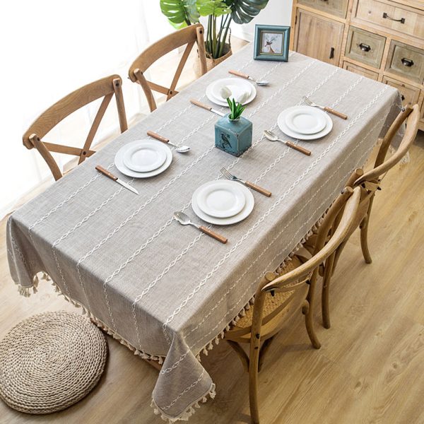 Beige faux linen tablecloth with white geometric embroidery and tassel fringe – perfect for modern dining rooms, cafés, or outdoor tables.