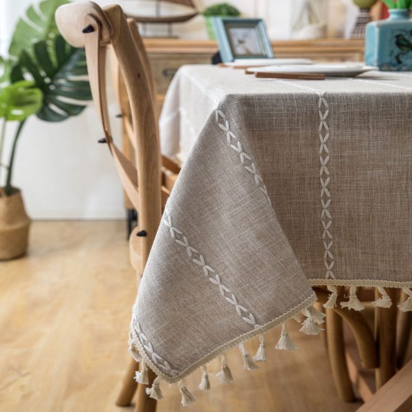 Beige faux linen tablecloth with white geometric embroidery and tassel fringe – perfect for modern dining rooms, cafés, or outdoor tables.