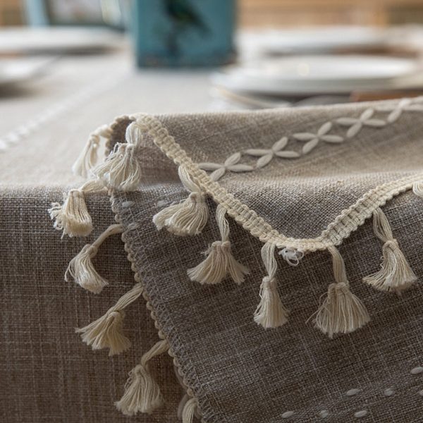 Beige faux linen tablecloth with white geometric embroidery and tassel fringe – perfect for modern dining rooms, cafés, or outdoor tables.